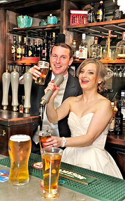 All hands to the pumps!: bride and groom pull pints to kick-off the reception