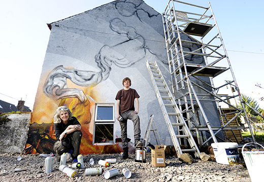 Artists Denise Zagadlo and Fraser Gray at their 'bonfire' mural at the gable end of a cottage in Keir Mill, near Thornhill